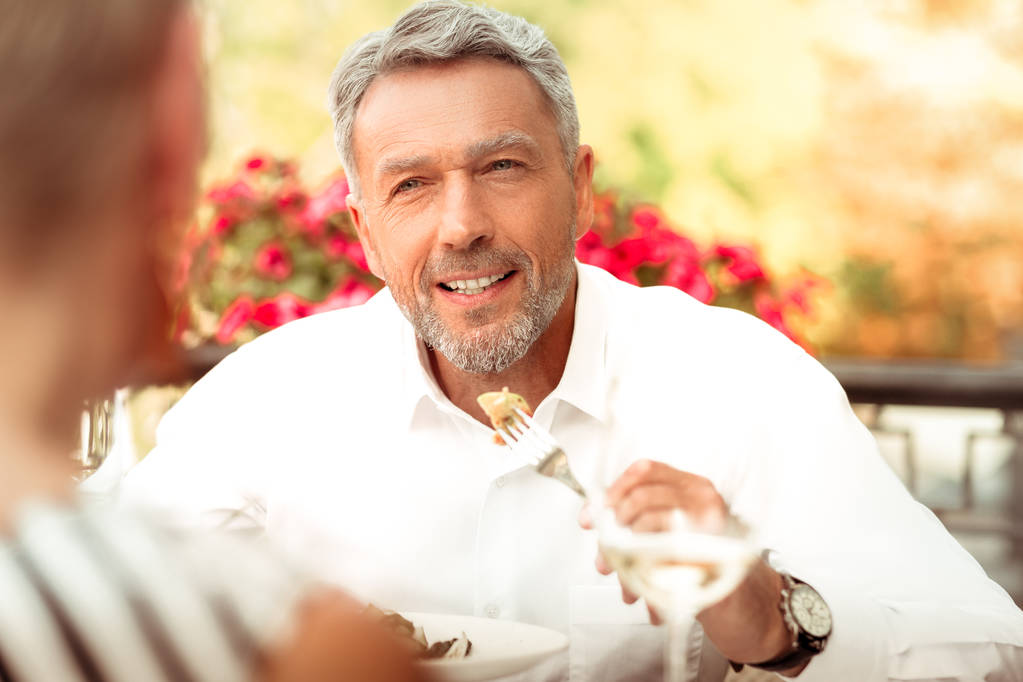 Handsome bearded mature man eating and talking to his wife - Photo, Image