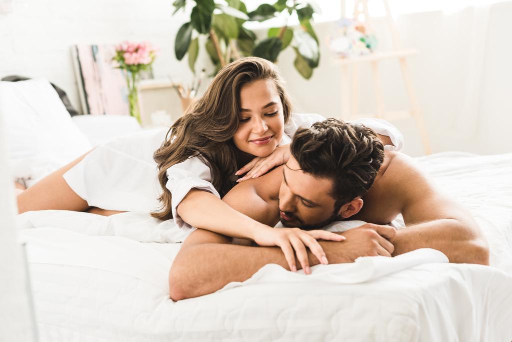 couple sexy couché dans le lit tandis que l'homme regarde loin et fille regardant petit ami
 - Photo, image