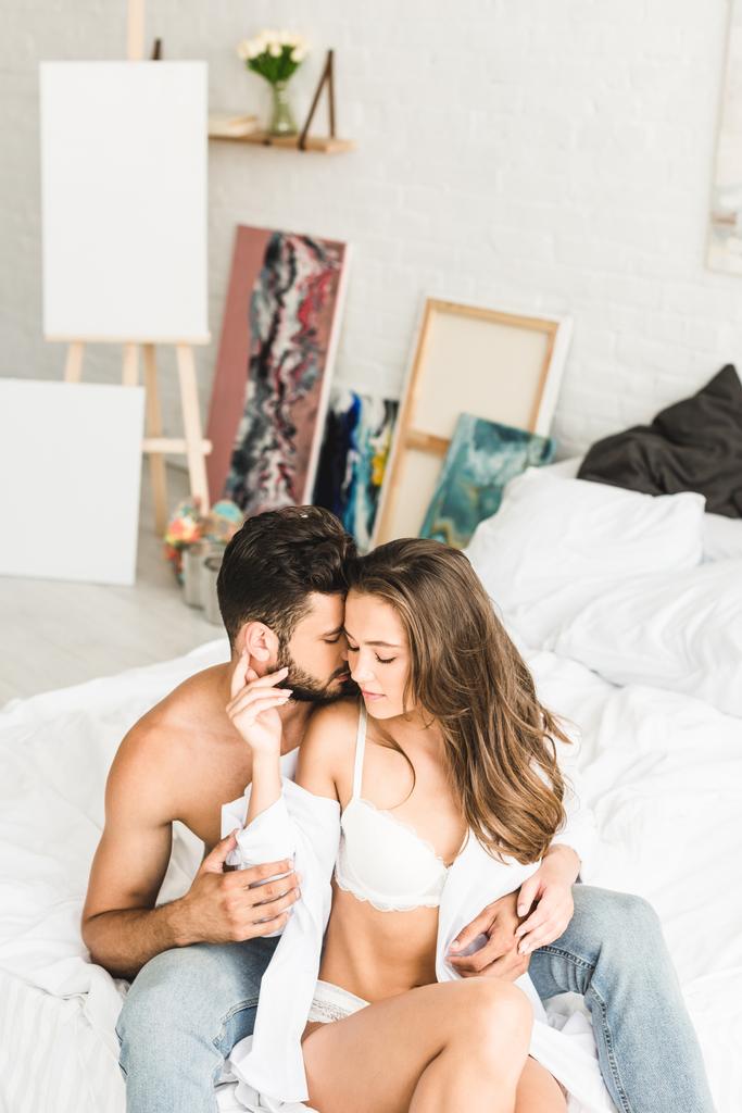 szexi pár ül az ágyban, míg az ember próbál csókolni lány a nyak - Fotó, kép