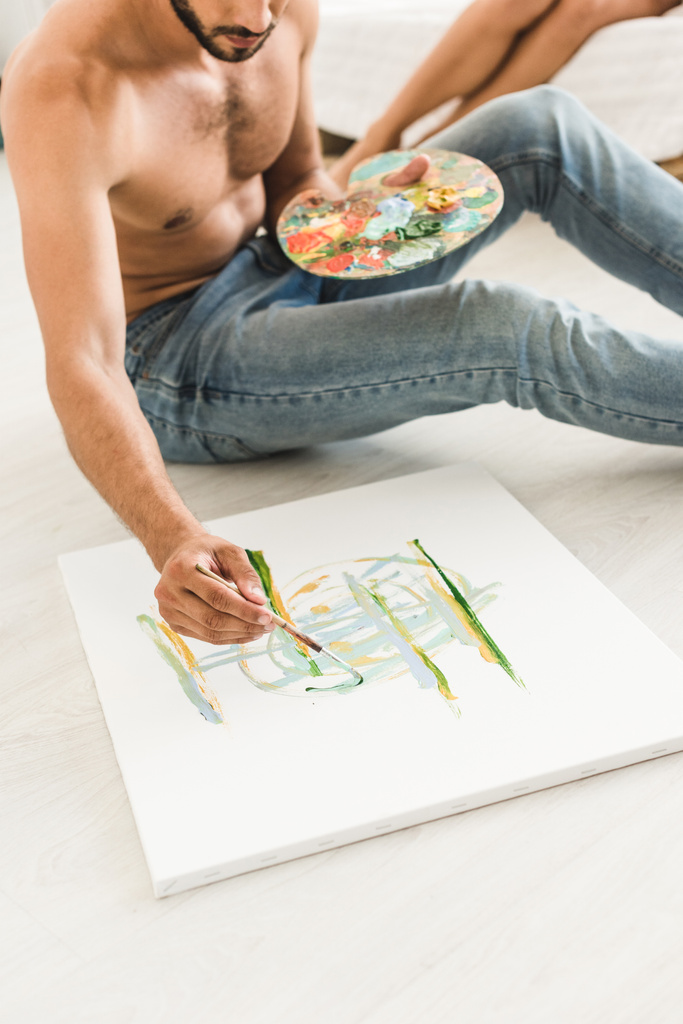 vista cortada do homem desenho com escova enquanto sentado no chão
 - Foto, Imagem