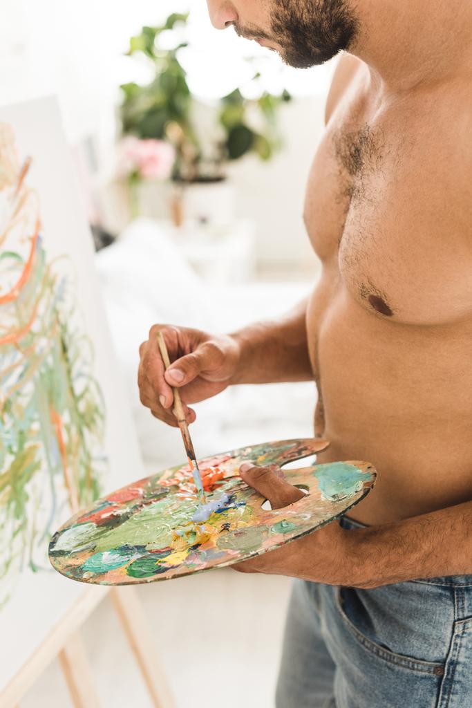 cropped view of sexy muscular man drawing with brush and colorful paints - Photo, Image