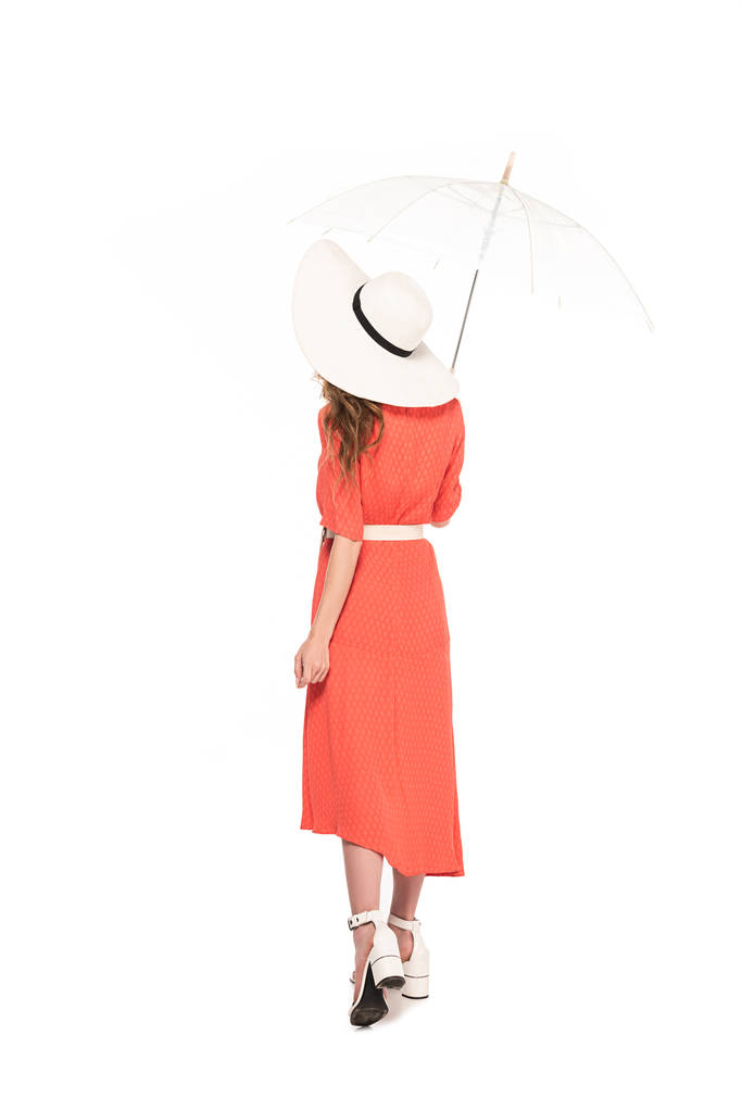 Widok z tyłu eleganckiej kobiety w kapeluszu i sukni trzymając przejrzysty parasol na białym tle - Zdjęcie, obraz