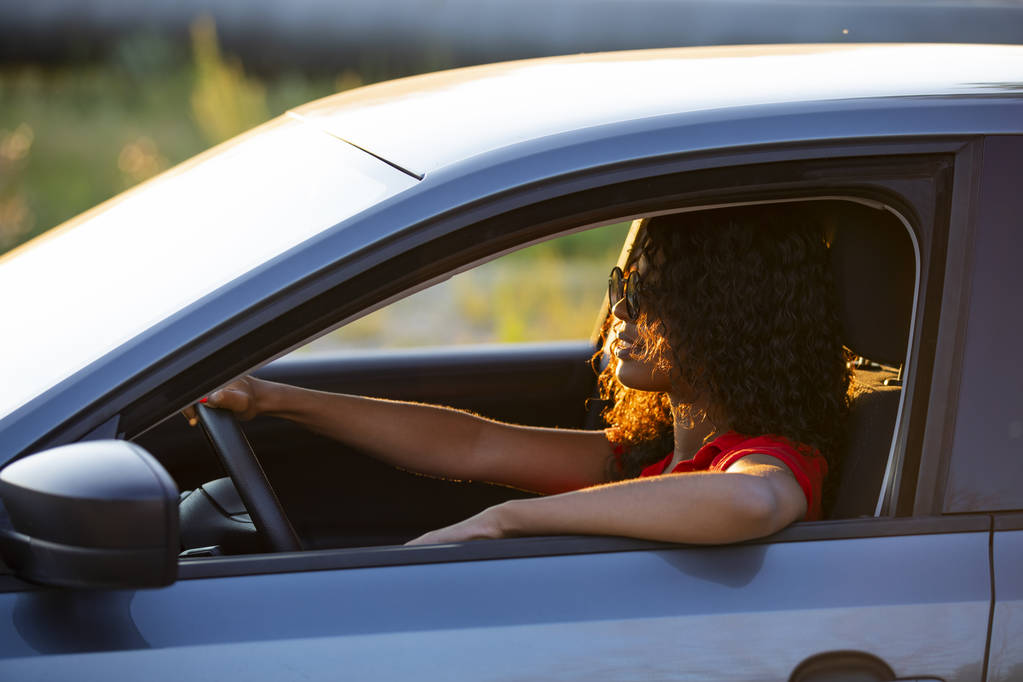Gün batımında araba salonunda oturan mutlu kadın sürücü - Fotoğraf, Görsel