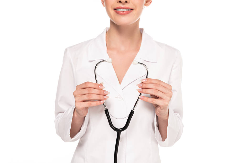 visão recortada de jovem médico sorridente em casaco branco segurando estetoscópio isolado em branco
 - Foto, Imagem