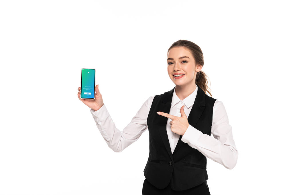KYIV, UCRANIA - 7 DE ABRIL DE 2019: joven camarera feliz señalando con el dedo a la aplicación de twitter en el teléfono inteligente aislado en blanco
 - Foto, Imagen