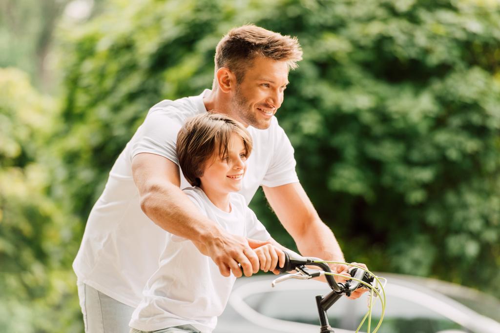 前を見ながら自転車のハンドルを握る父と息子の選択的な焦点 - 写真・画像