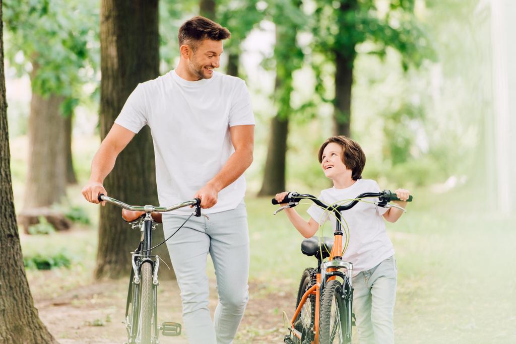 focus selettivo di padre e figlio con biciclette che si guardano
 - Foto, immagini