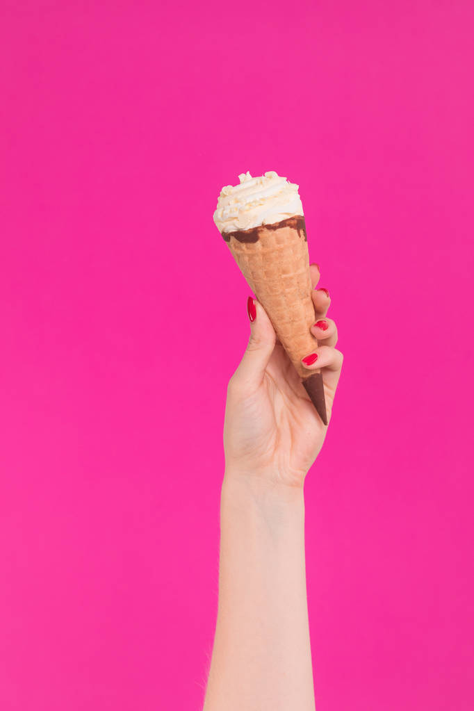 Жіноча рука тримає морозиво у вафельному конусі
 - Фото, зображення