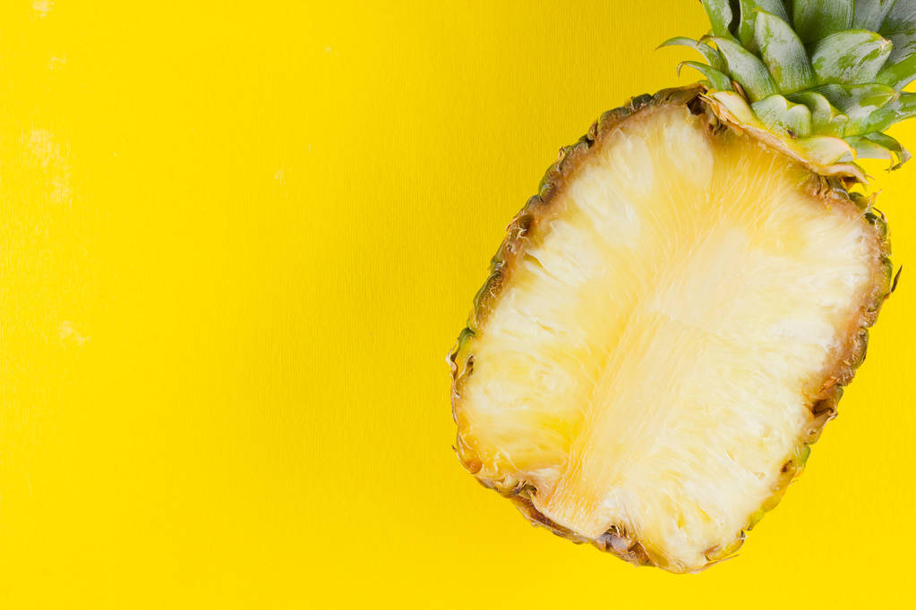 Ananas auf gelbem Hintergrund. Ananashälfte auf pastellfarbenem Hintergrund. Tropische Früchte im Pop-Art-Stil. Minimalismus. Kopierraum - Foto, Bild