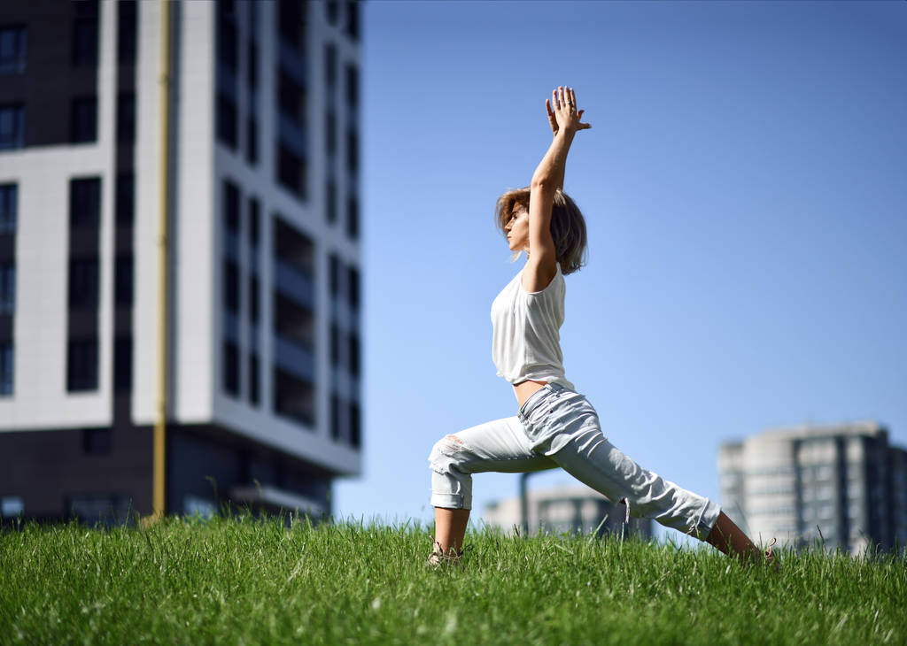 Nuori nainen tekee jooga venyttely harjoituksia kaupunkien moderni kaupunkipuisto
 - Valokuva, kuva