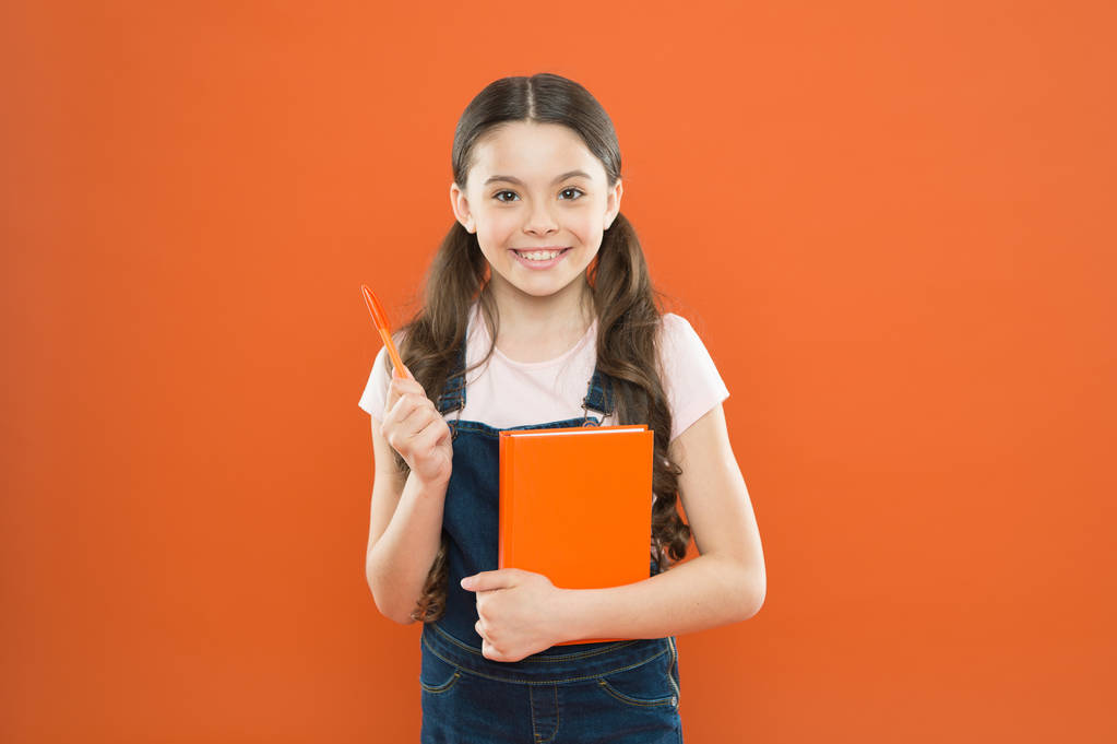 A kutatás során. Irodalom lecke. vissza az iskolába. boldog kislány notebook. iskolás lány olvasni könyvet narancssárga háttérben. jegyzetírás. gyerek naplót. költészet és regény. modern oktatásért - Fotó, kép