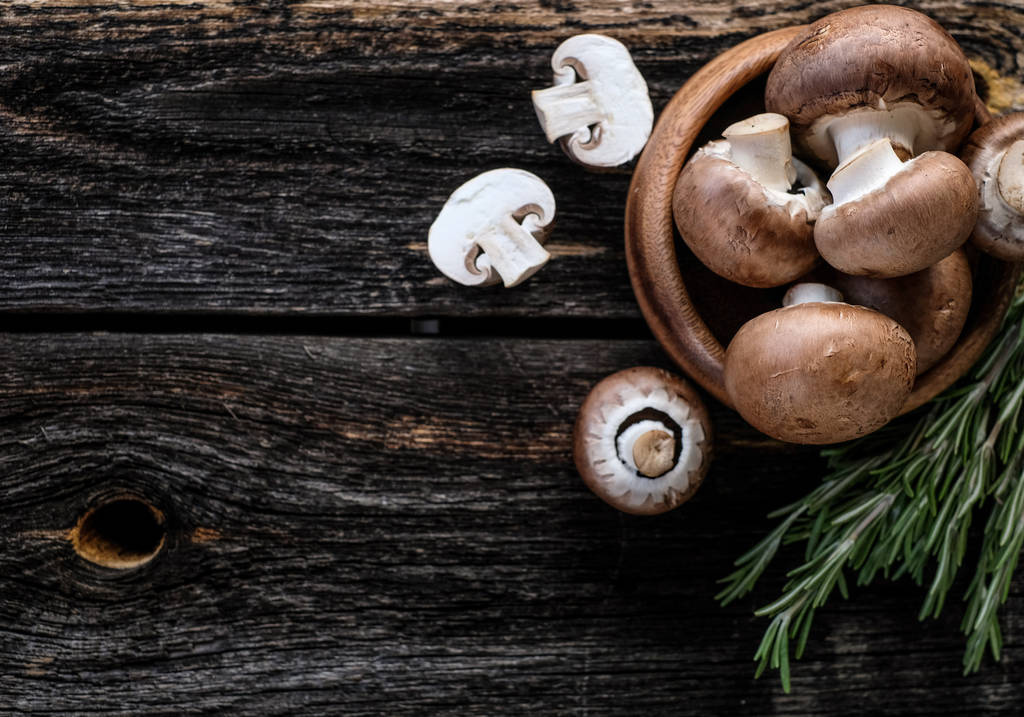 Bruine paddenstoelen op oude donkere houten achtergrond - Foto, afbeelding