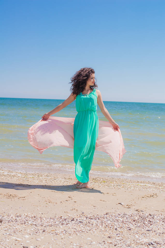 Fiatal lány a strandon, nyáron pedig egy gyönyörű ruhát egy repülő kendő  - Fotó, kép