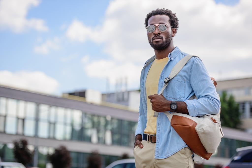 komea afrikkalainen amerikkalainen mies aurinkolaseissa katselee pois pitäen kädestä taskussa
 - Valokuva, kuva