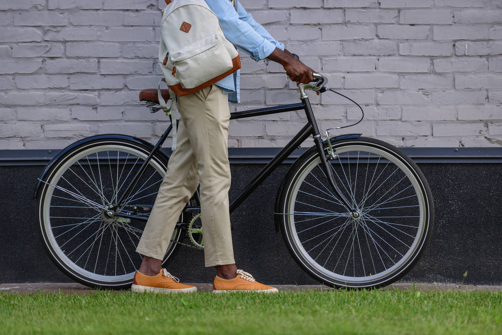 nyírt kilátás afroamerikai férfi álló kerékpáros közelében téglafal - Fotó, kép