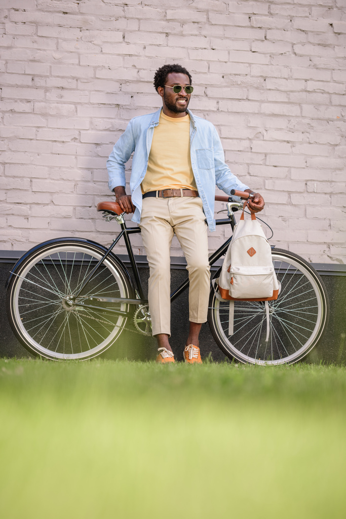 selective focus of stylish african american man standing with bicycle near brick wall - Photo, Image