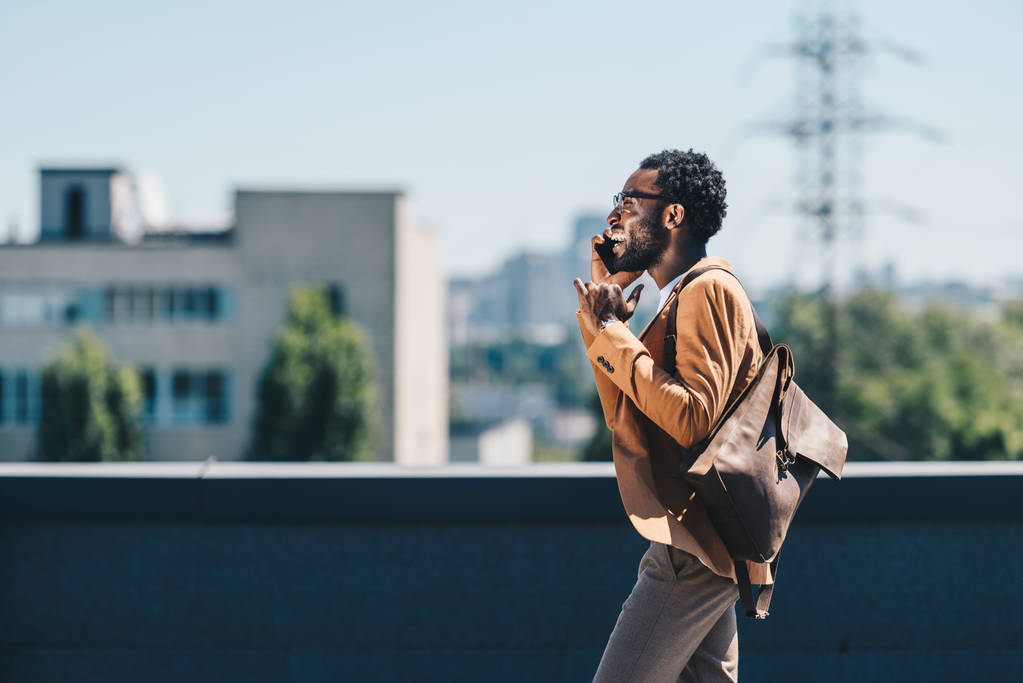 stijlvolle Afro-Amerikaanse zakenman praten op een smartphone tijdens het lopen op het dak - Foto, afbeelding