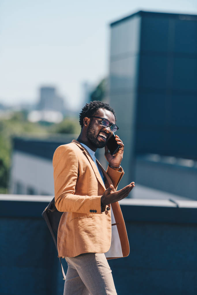 heyecanlı Afrikalı Amerikalı işadamı akıllı telefon konuşuyor ve çatı üzerinde gesturing - Fotoğraf, Görsel