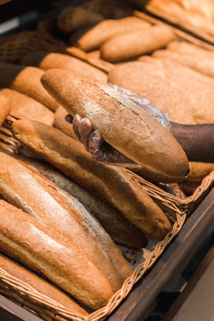 vista recortada del hombre afroamericano sosteniendo baguette en el supermercado
  - Foto, Imagen