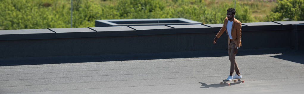 panoramische foto van African American zakenman Longboarden op Sunny Rooftop - Foto, afbeelding