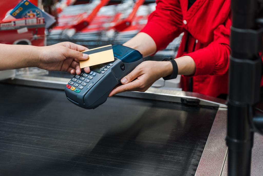 обрізаний вид клієнта, що платить кредитною карткою біля касиру в супермаркеті
  - Фото, зображення