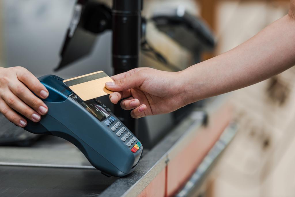 обрізаний вид чоловіка, який платить кредитною карткою біля касиру в супермаркеті
  - Фото, зображення