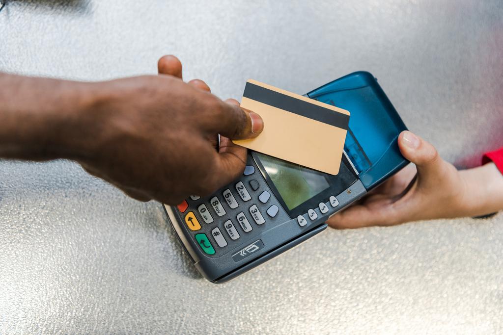 обрезанный вид на африканского американца, платящего кредитной картой возле кассира в супермаркете
  - Фото, изображение