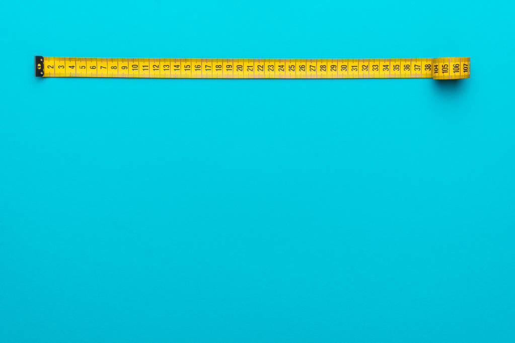 Вид зверху на жовту вимірювальну стрічку на бірюзово-блакитному фоні з пробілом для копіювання
 - Фото, зображення