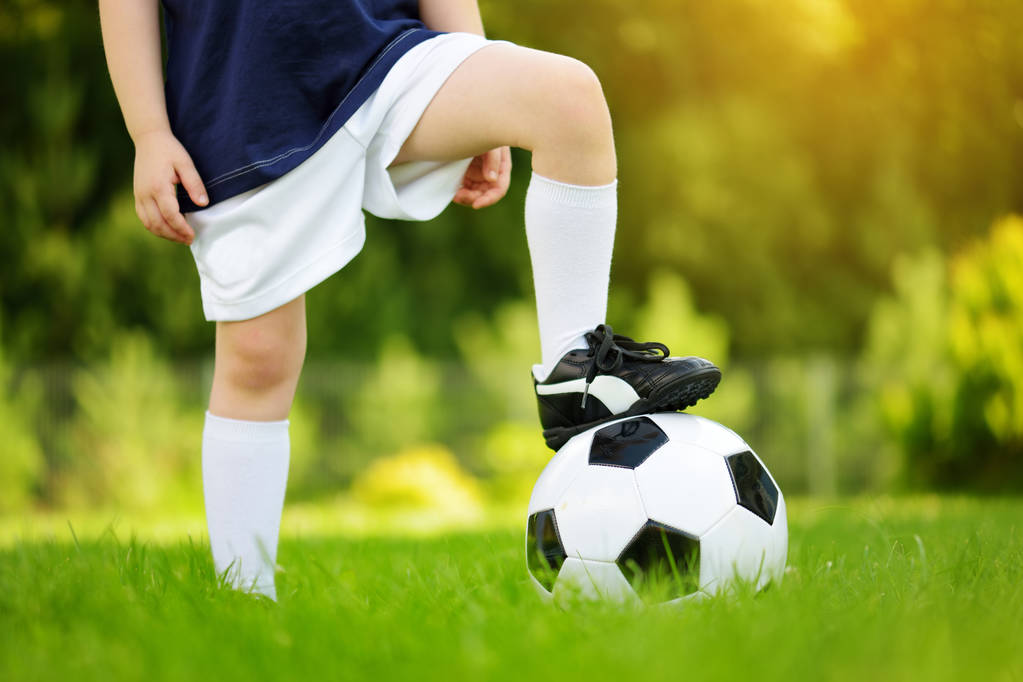 Güneşli yaz gününde futbol oynarken eğlenen bir çocuğun yakın çekim. Çocuklar için spor aktiviteleri. - Fotoğraf, Görsel