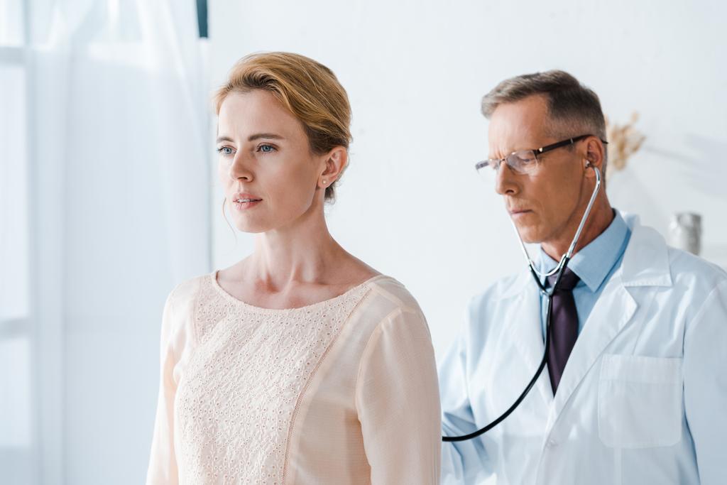 schöner Arzt mit Brille untersucht attraktive Frau in Klinik  - Foto, Bild