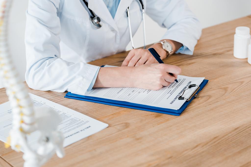 обрезанный взгляд врача, пишущего диагноз на деревянном столе
  - Фото, изображение