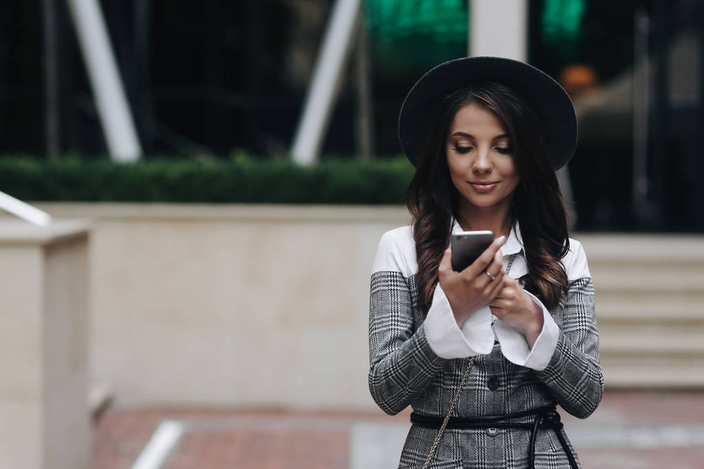 通りでスマートフォンを使用して幸せな女性。若いbの肖像 - 写真・画像