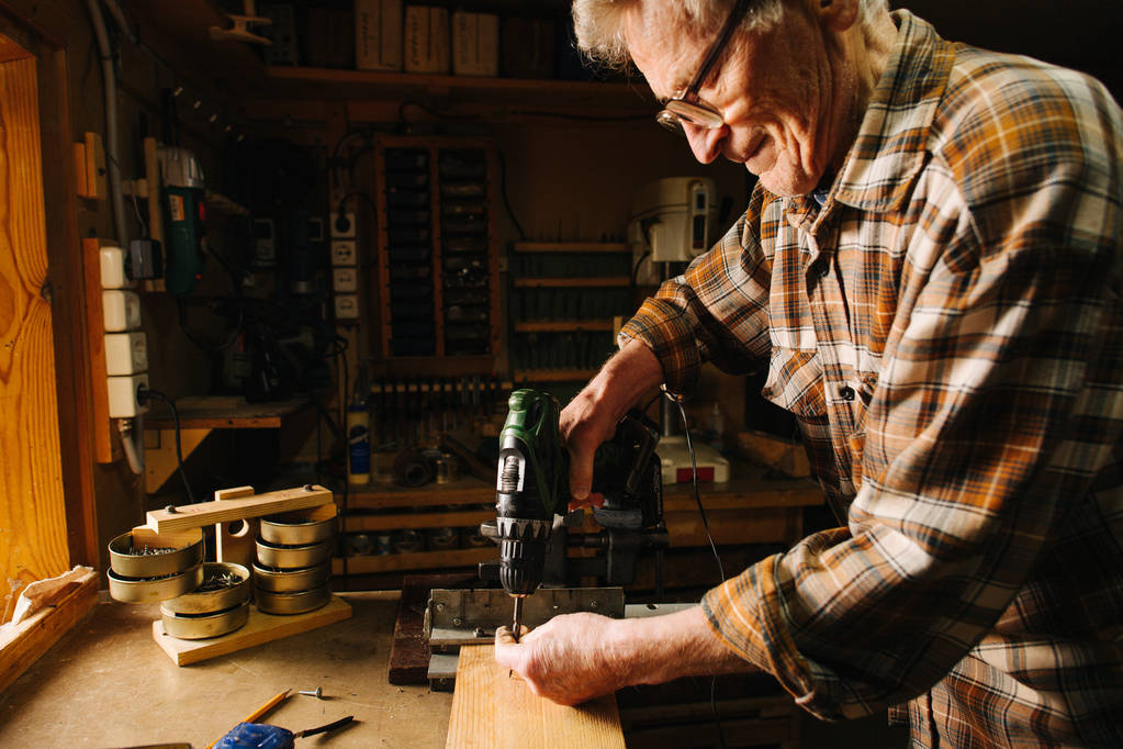 Onun tezgahta Amatör kıdemli marangoz, el matkap kullanarak - Fotoğraf, Görsel