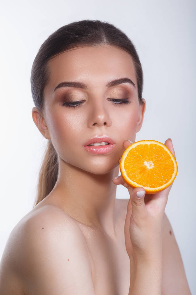 Beautiful woman with natural make up and orange on white background. - Photo, Image