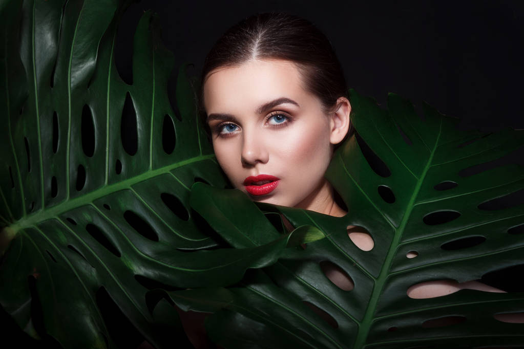 красива жінка з макіяжем і червоними губами в зеленому листі
 - Фото, зображення