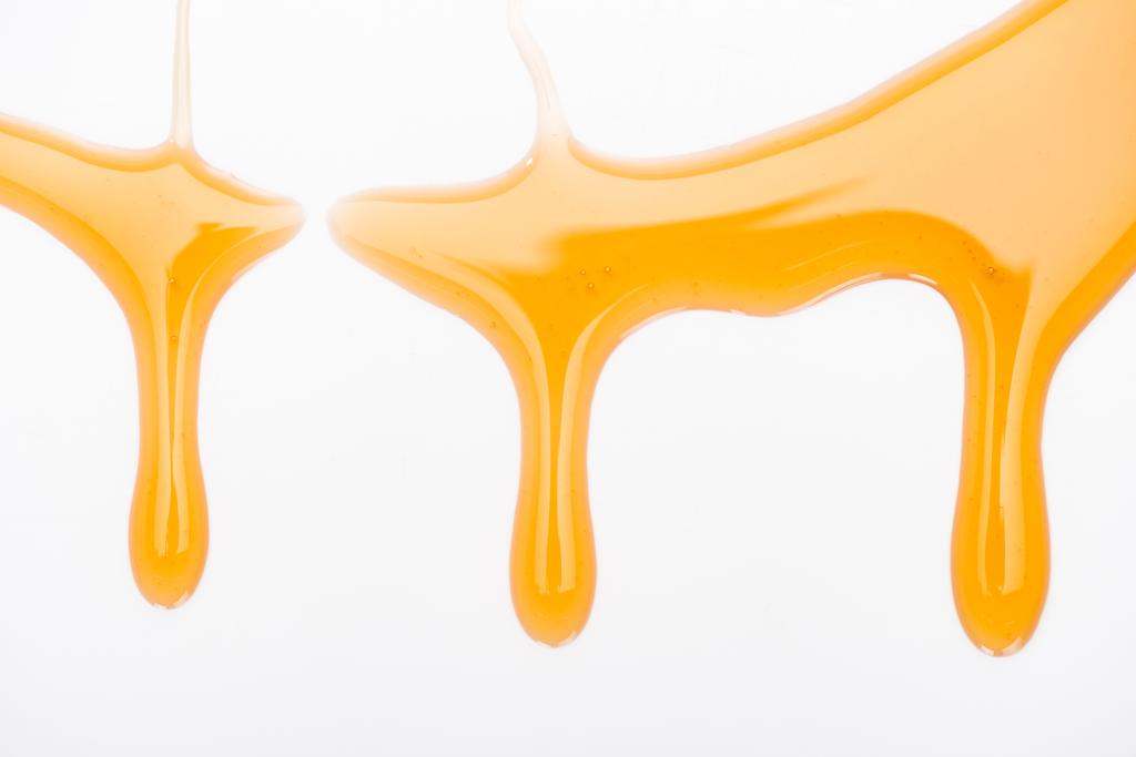 закрыть вид на капающий сладкий вкусный мед, изолированный на белом
  - Фото, изображение
