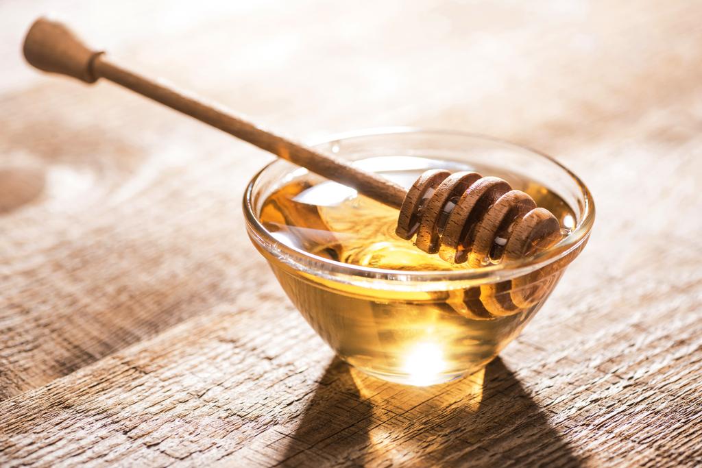 tarro con miel y tarro de miel sobre mesa de madera a la luz del sol
 - Foto, Imagen