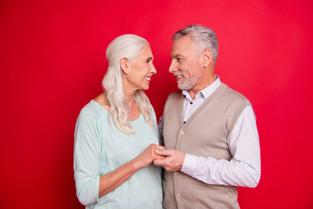 Close up photo amazing beautiful she he he he he his aged guy lady standing hugging sincere holding hands arms look eyes best partners wear sweater jersey shirt waistcoat isolated red background
 - Foto, Imagen