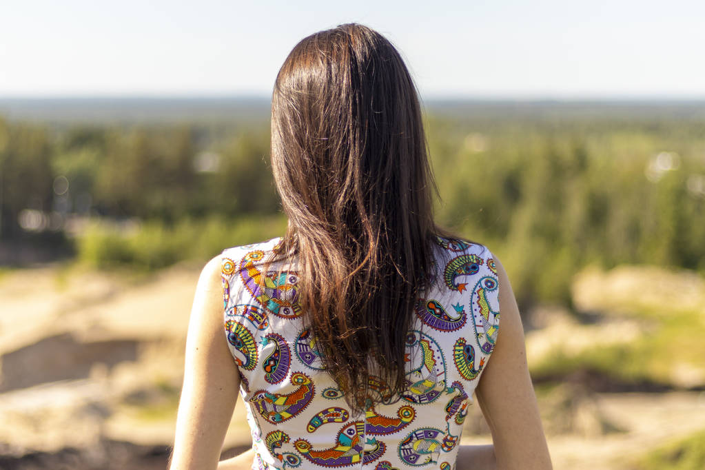 Una giovane ragazza sta con la schiena sullo sfondo della foresta
 - Foto, immagini