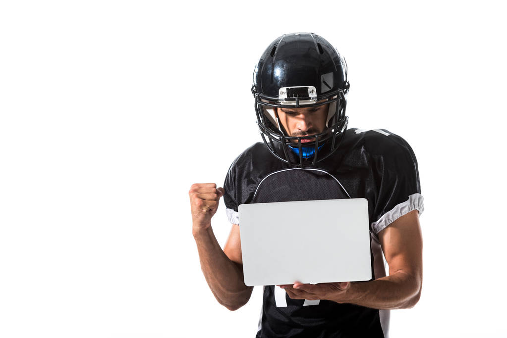 Αμερικανός ποδοσφαιριστής με φορητό υπολογιστή ζητωκραυγάζει με σφικτό χέρι απομονωμένη σε λευκό - Φωτογραφία, εικόνα