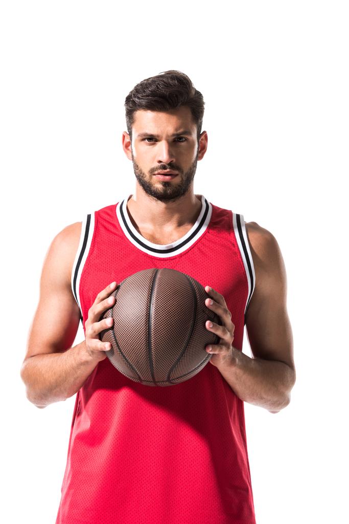 sportieve basketbalspeler Holding Ball en kijken naar camera geïsoleerd op wit  - Foto, afbeelding