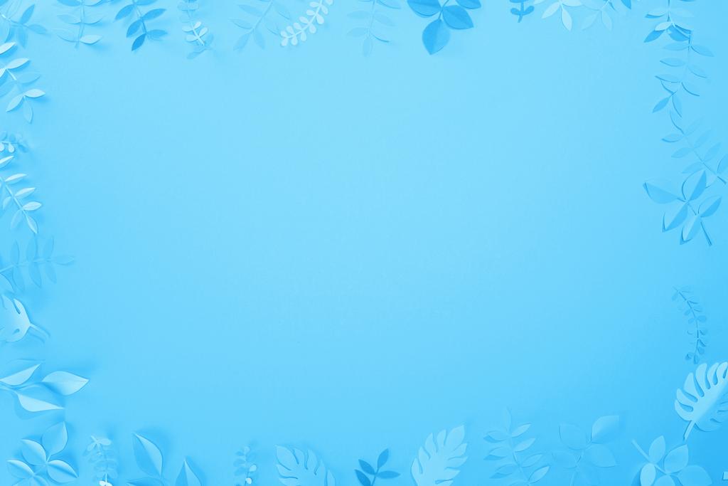 コピースペースを持つ青いミニマルな背景に紙カットの葉のフレーム - 写真・画像