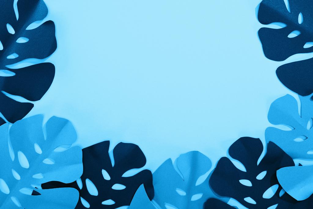 вид зверху на папір вирізане тропічне листя на синьому мінімалістичному фоні з пробілом для копіювання
 - Фото, зображення