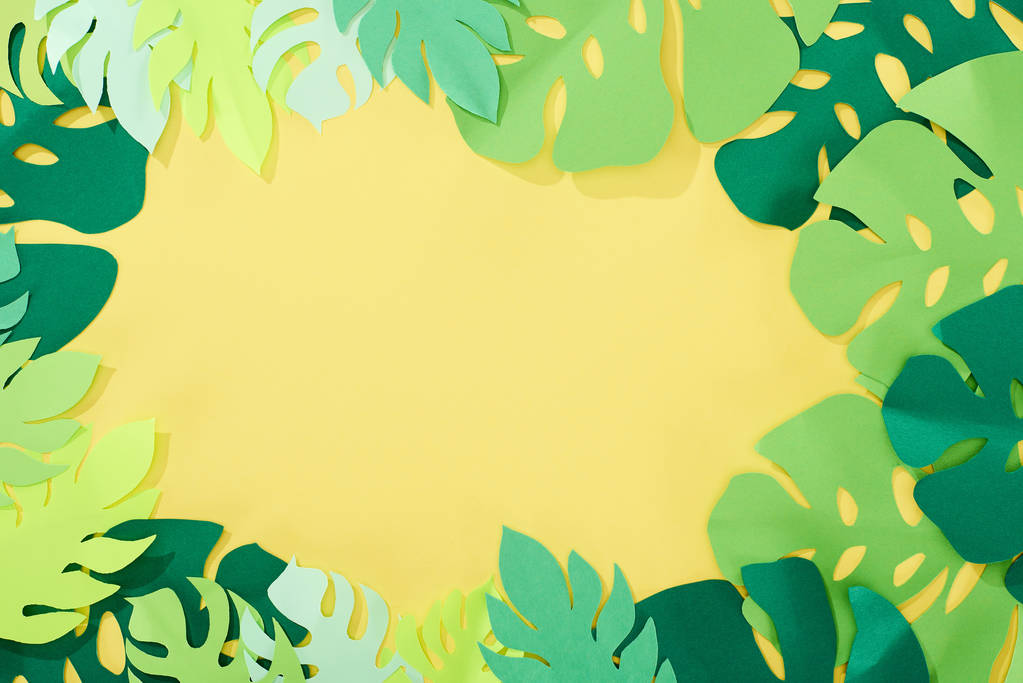 Widok z góry papieru wycięte zielone tropikalne liście na żółtym jasnym tle z kopią przestrzeni - Zdjęcie, obraz