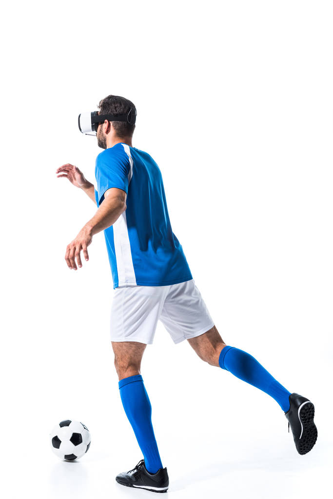 Achteraanzicht van de voetballer in Virtual Reality headset training met bal geïsoleerd op wit - Foto, afbeelding
