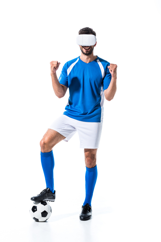 Soccer Player in Virtual Reality headset met bal juichen met gebalde handen geïsoleerd op wit - Foto, afbeelding
