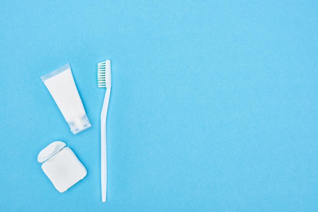vue du dessus de la brosse à dents et du dentifrice près des dents fil dentaire isolé sur bleu
  - Photo, image