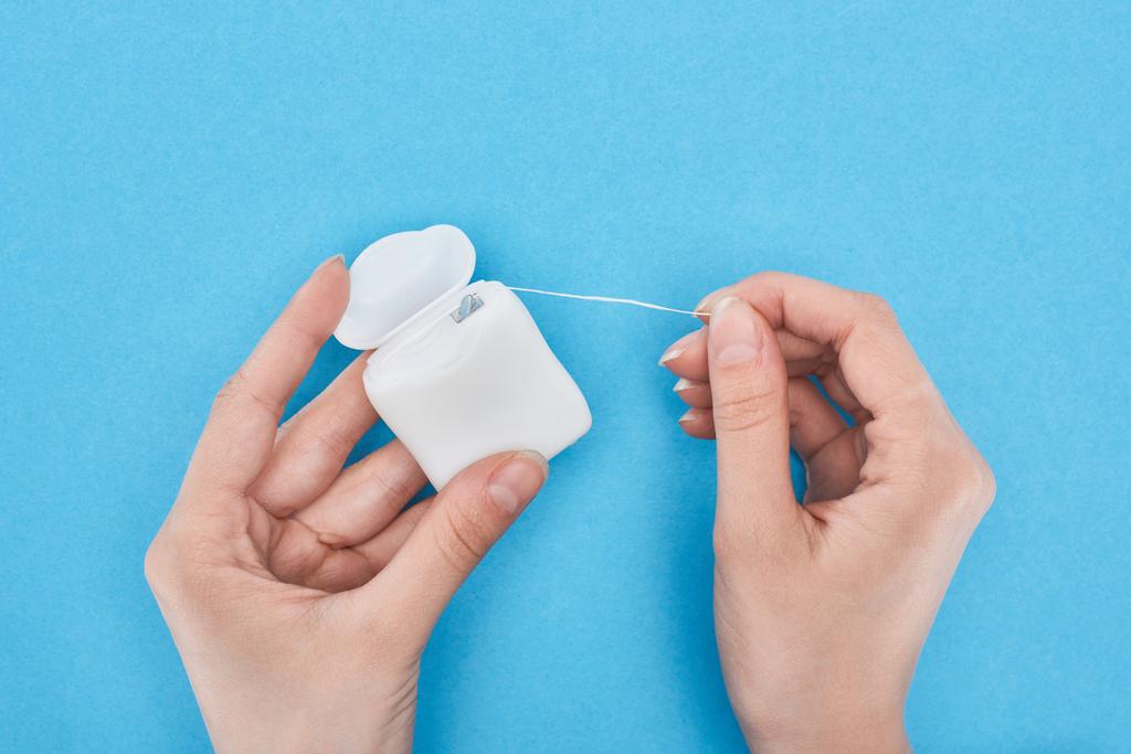 cropped view of woman holding dental floss on blue - Photo, Image