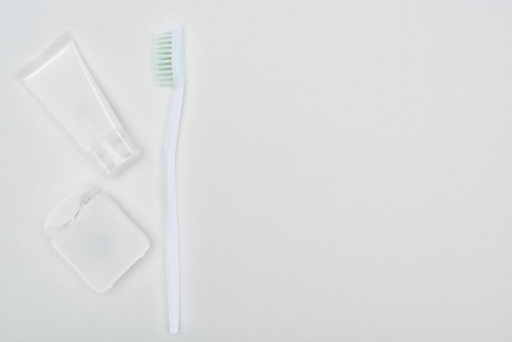 верхний вид зубной щетки и зубной пасты рядом с зубной нитью изолированы на белом
 - Фото, изображение