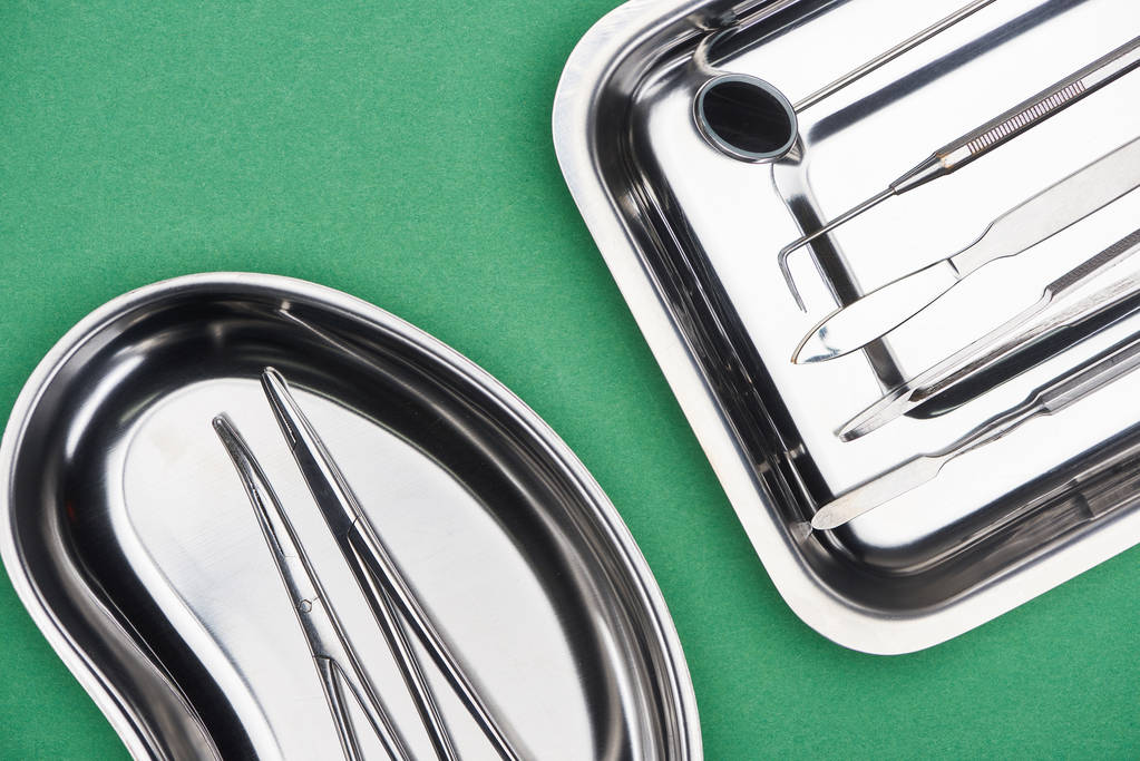 top view of set with dental tools in metallic plates isolated on green  - Photo, Image